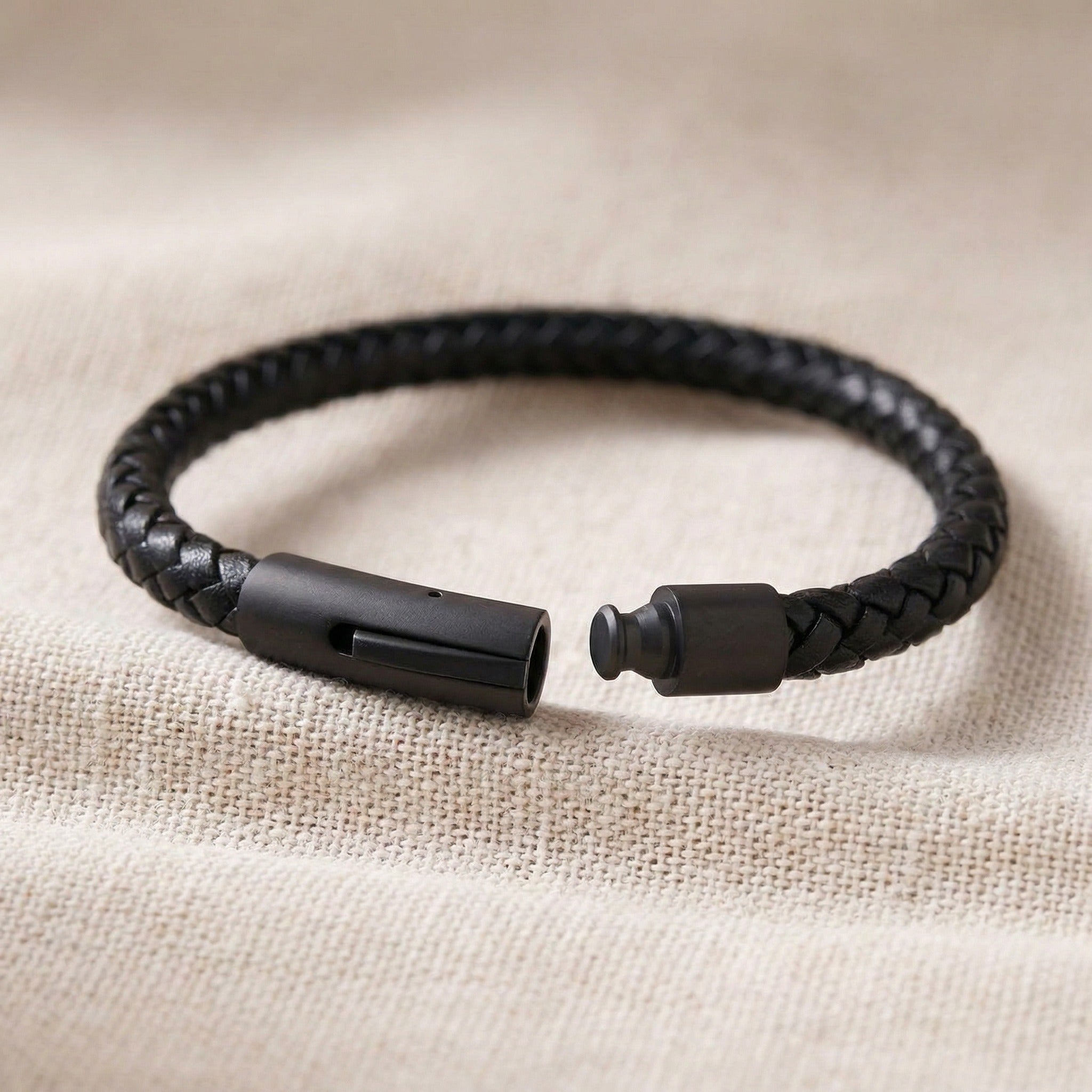 Black braided bracelet on a beige fabric background