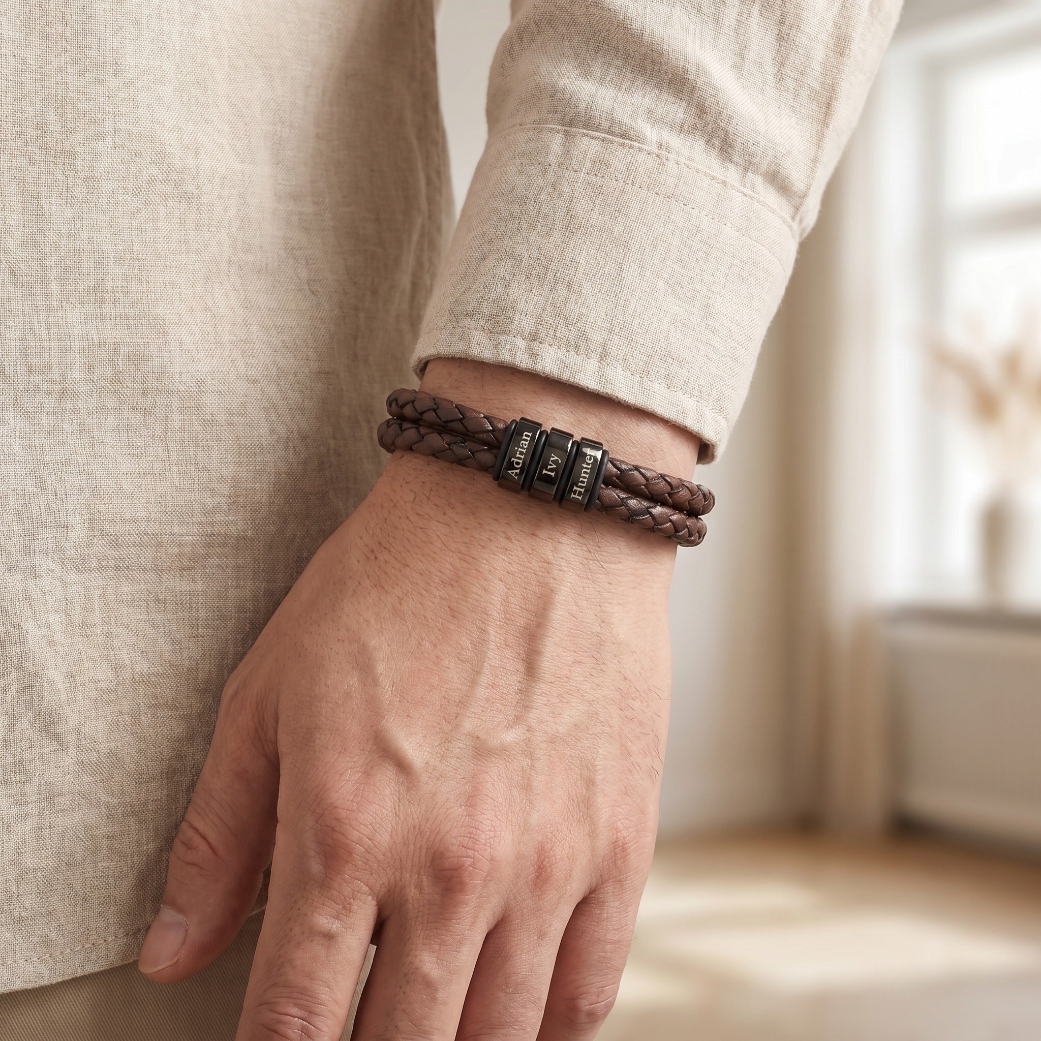 Person wearing a braided leather bracelet on a blurred indoor background