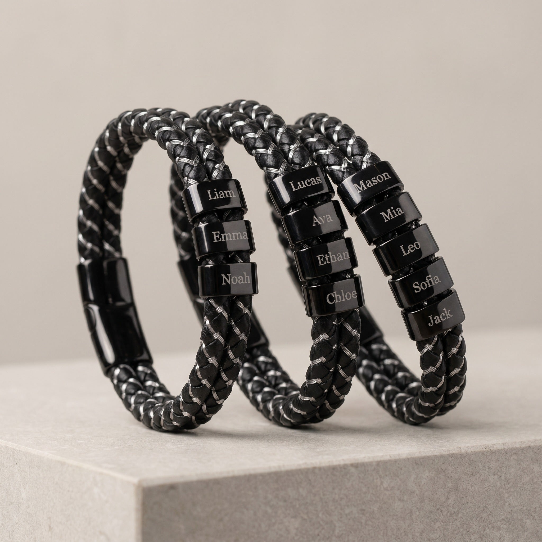 Black braided bracelets with name tags on a light gray surface