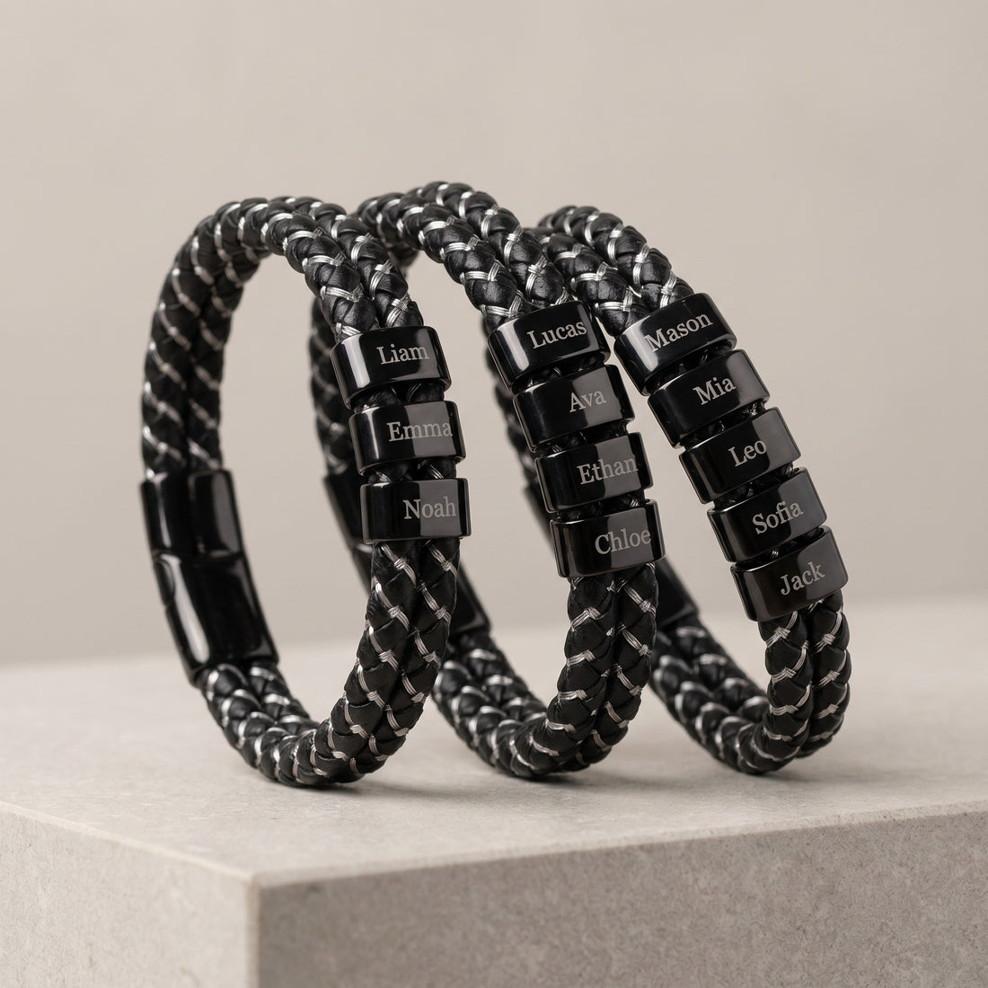 Black braided bracelets with name tags on a light gray surface