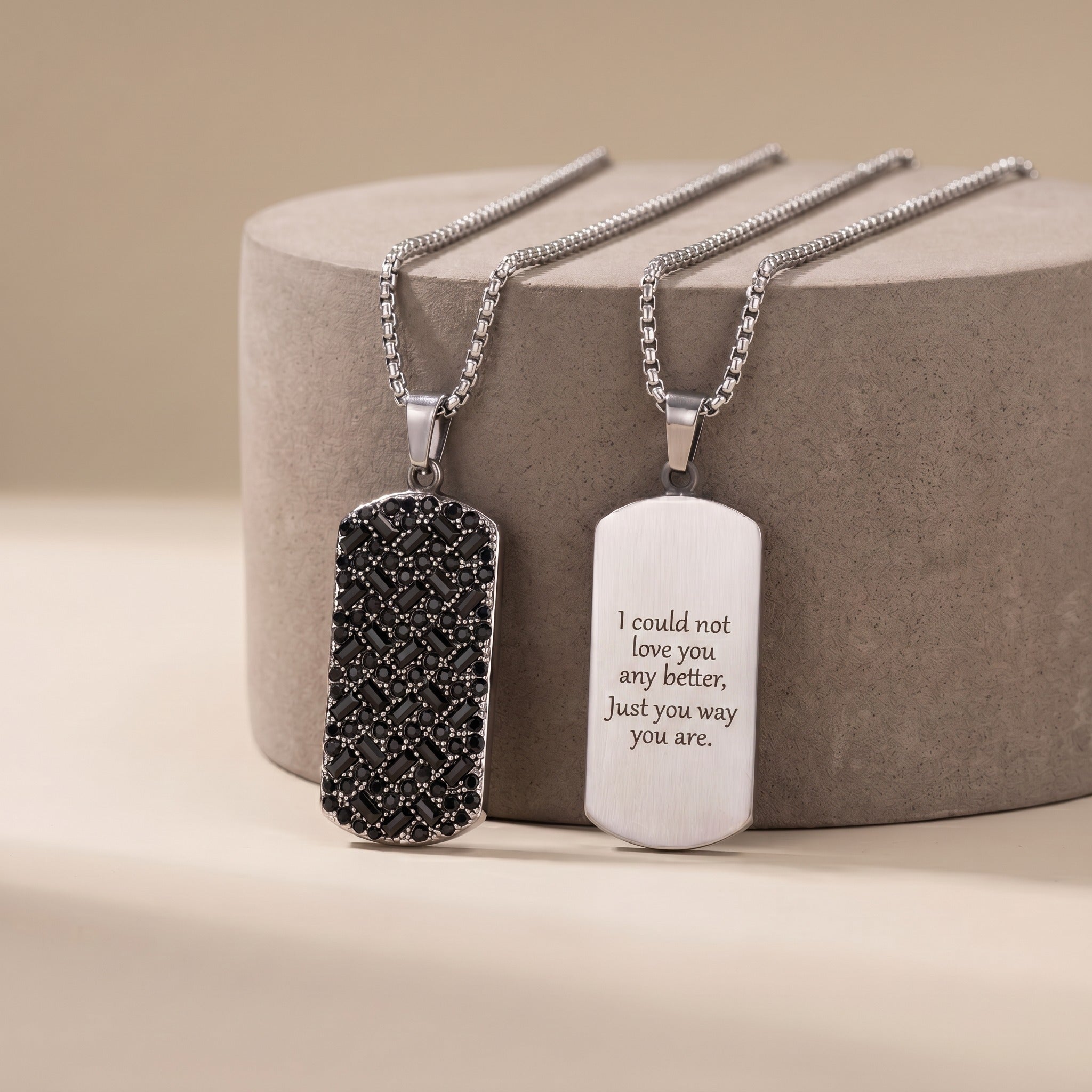 Two silver necklaces with engraved pendants on a beige background