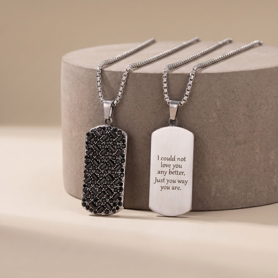 Two silver necklaces with engraved pendants on a beige background