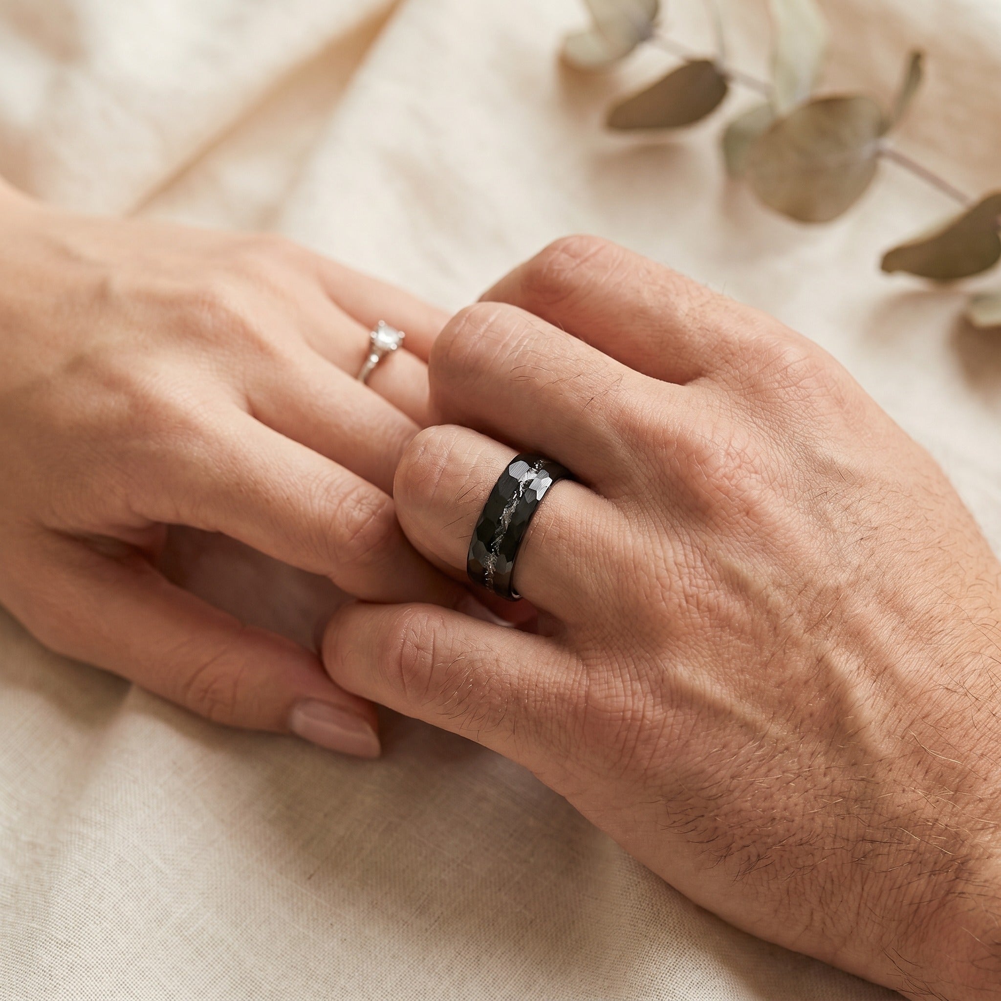 Close-up of two hands with rings on a soft beige background