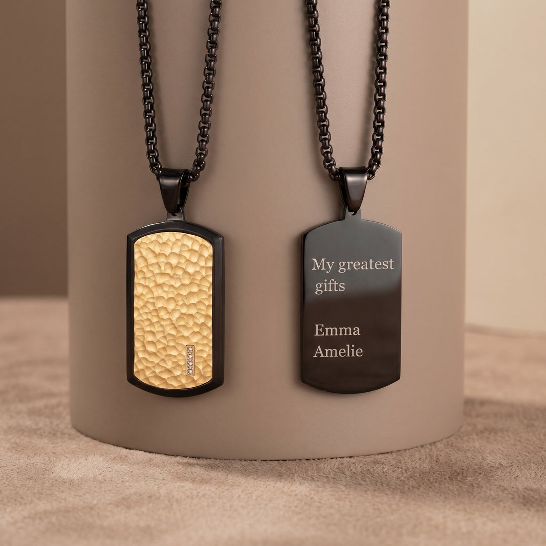 Two dog tag necklaces on a cylindrical beige stand with engraved text.