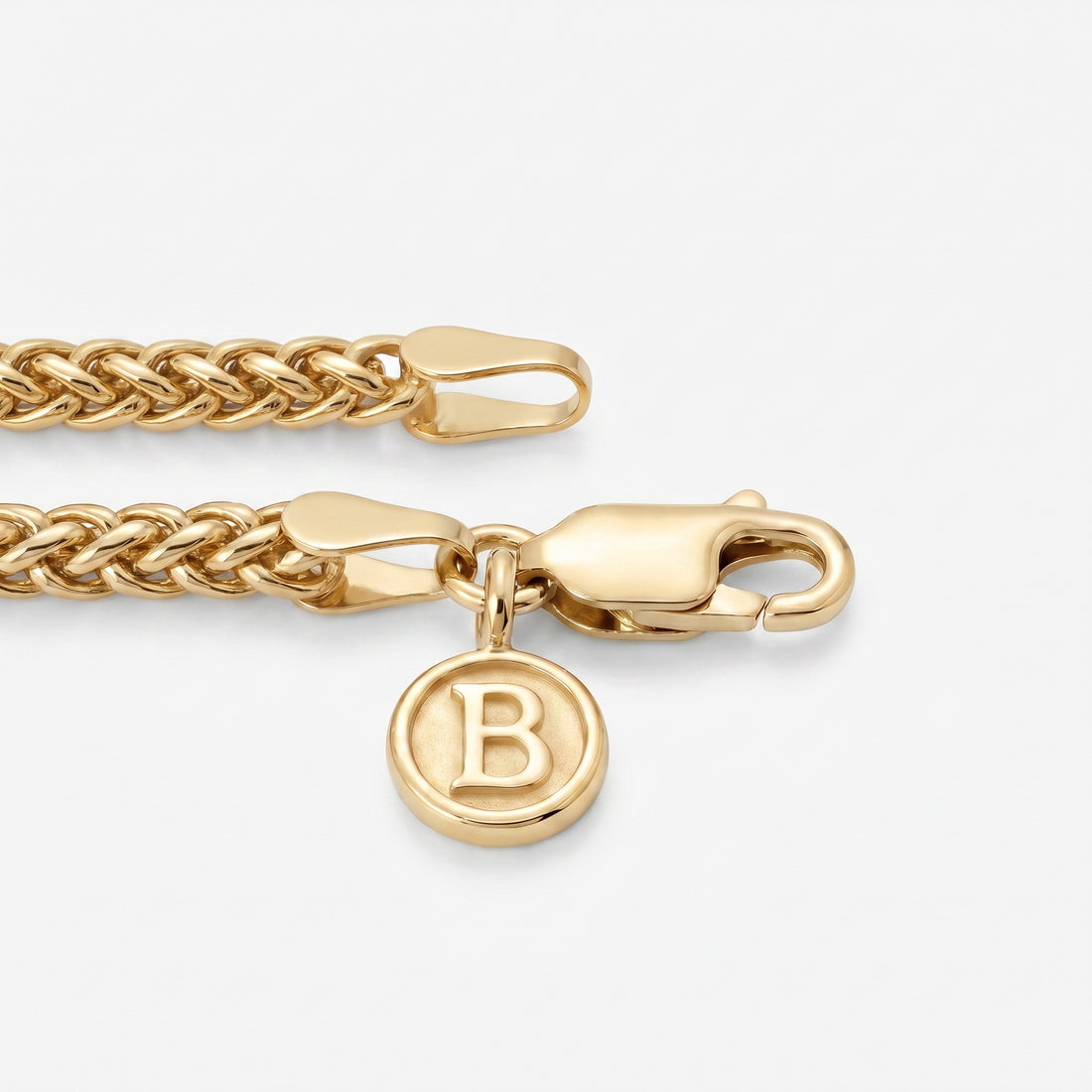 Gold chain necklace with a round pendant featuring the letter 'B' on a white background
