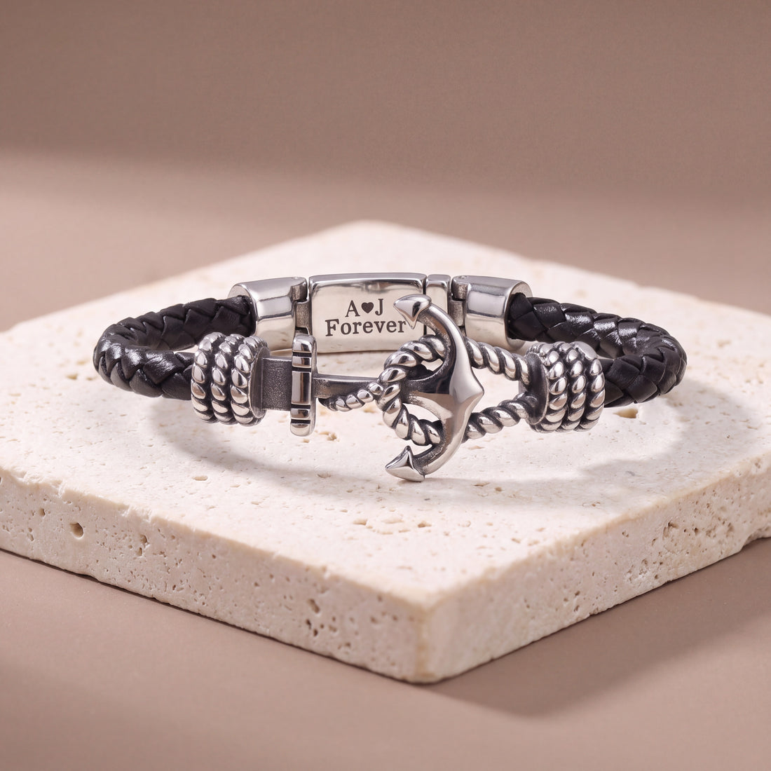 Close-up of the stainless steel anchor on a black braided leather bracelet