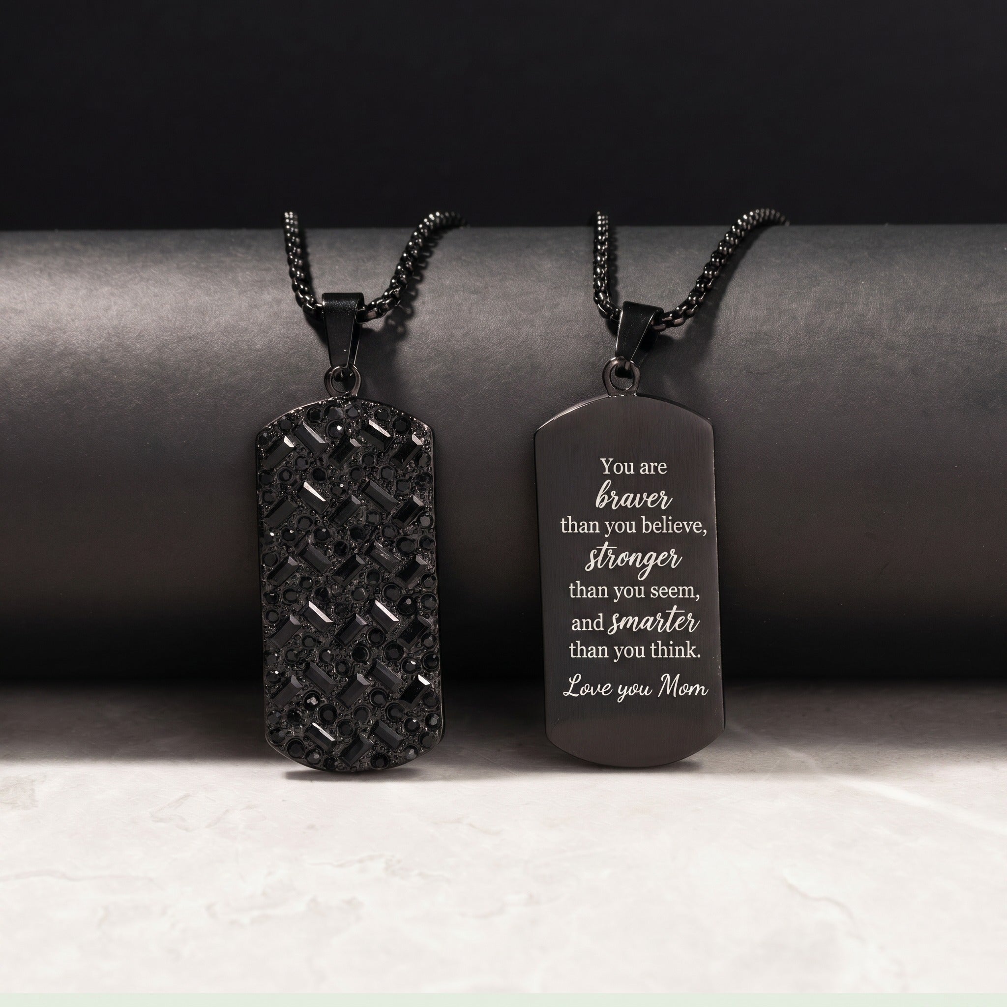 Two black dog tag necklaces on a dark background