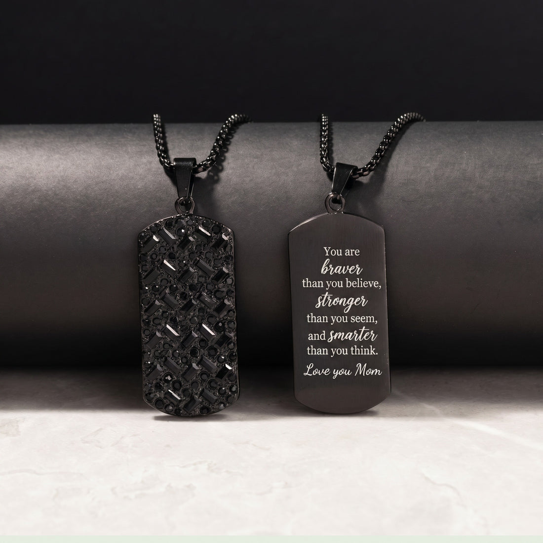 Two black dog tag necklaces on a dark background