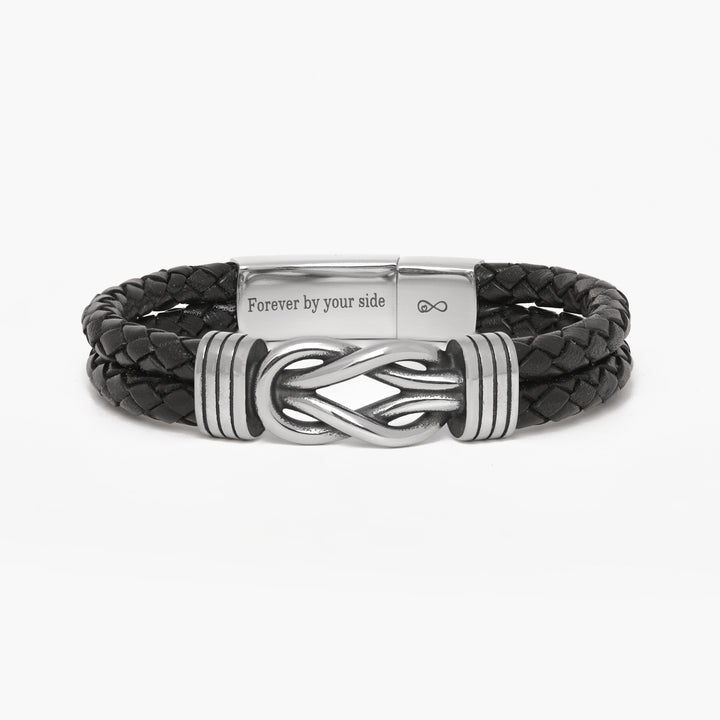 A black braided leather bracelet with a polished silver-tone metal clasp featuring an infinity symbol and the engraved text 'Forever by your side'.