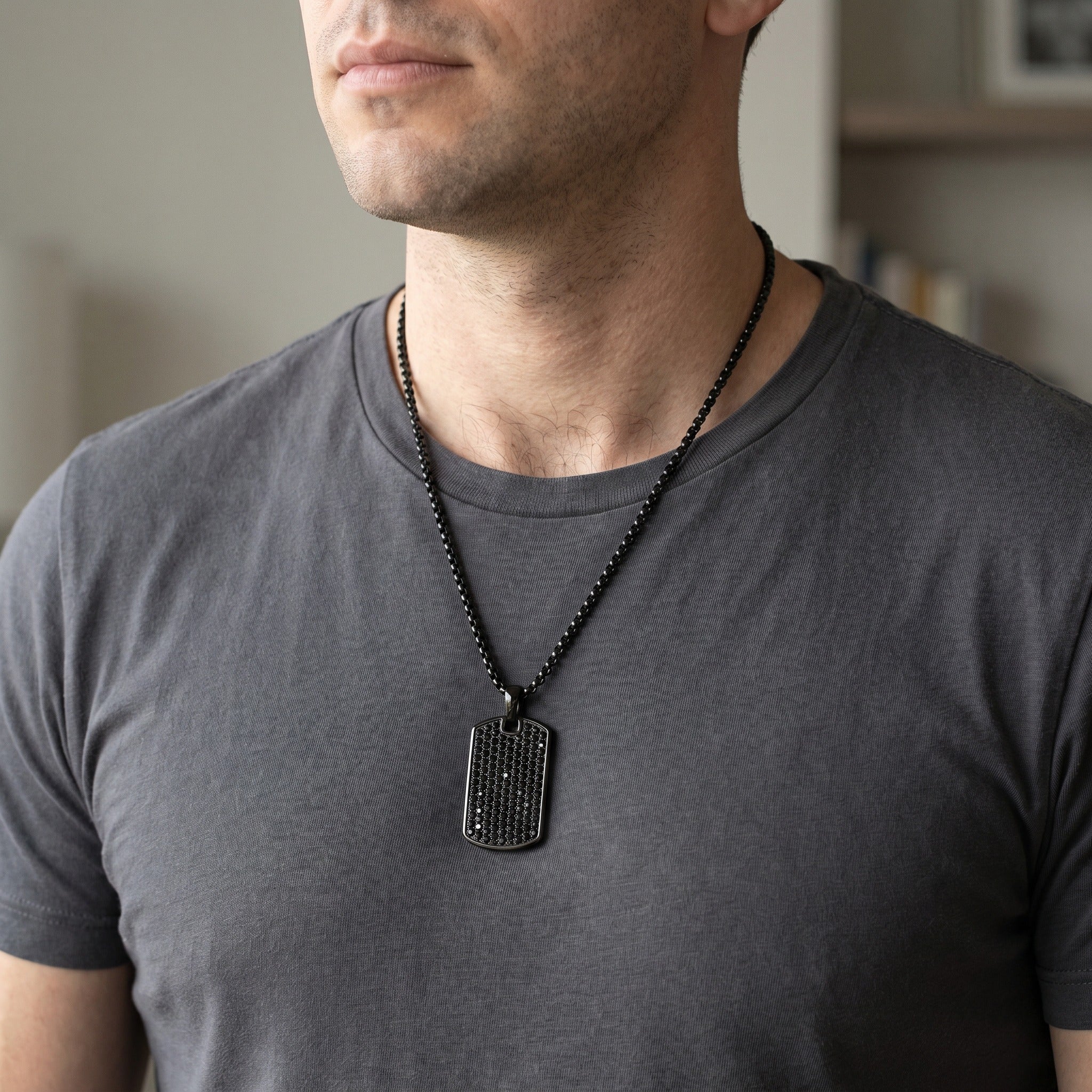 Man wearing a gray t-shirt with a black beaded necklace and dog tag.
