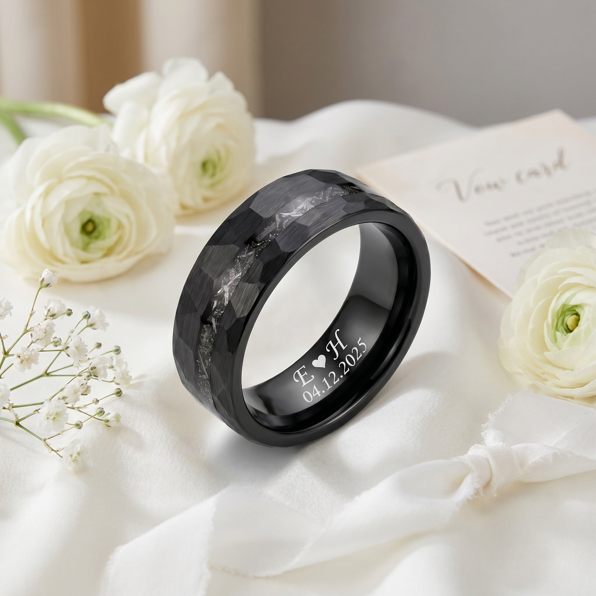 Black marbled ring with engraved text on a white fabric background with flowers