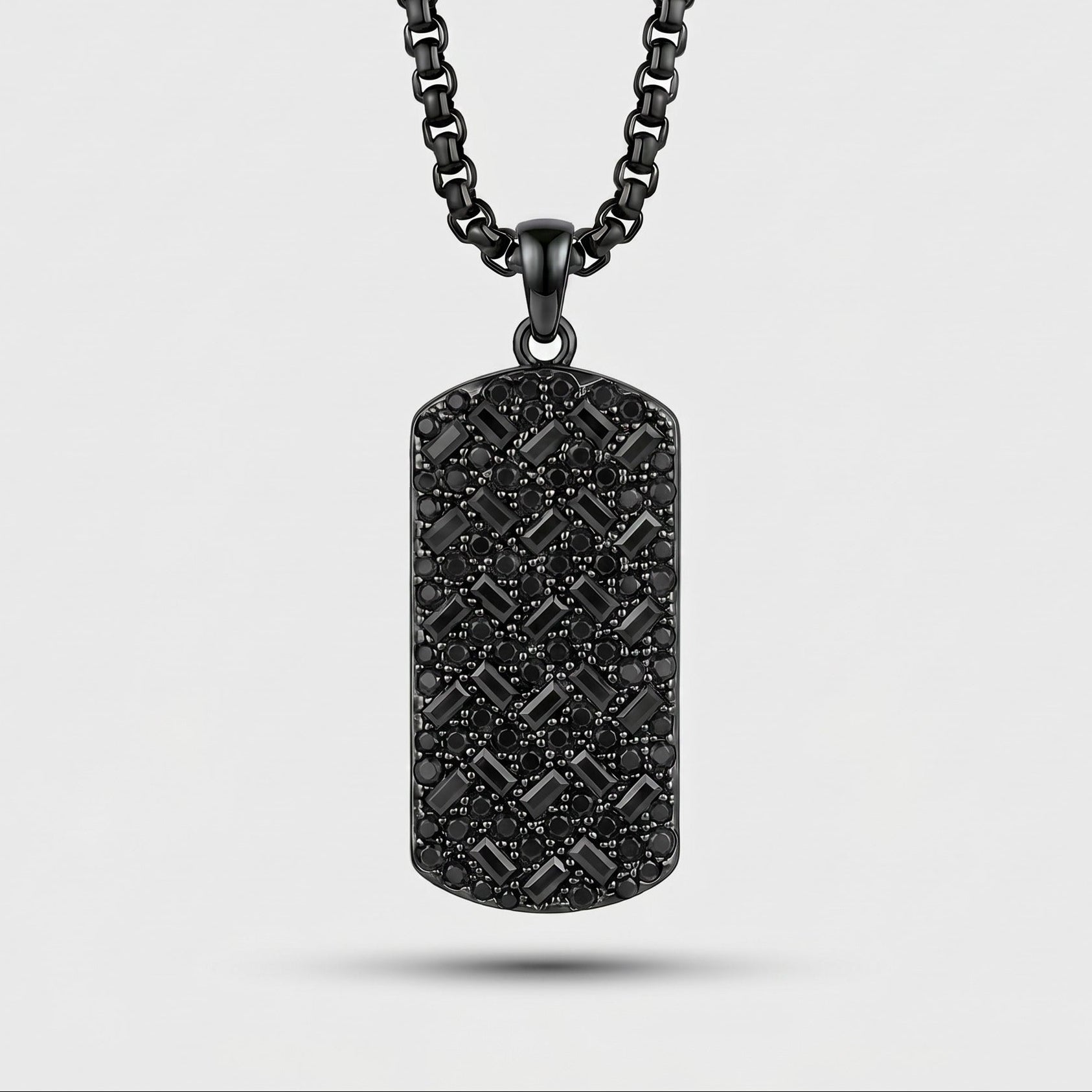 Black textured dog tag pendant on a chain against a light gray background