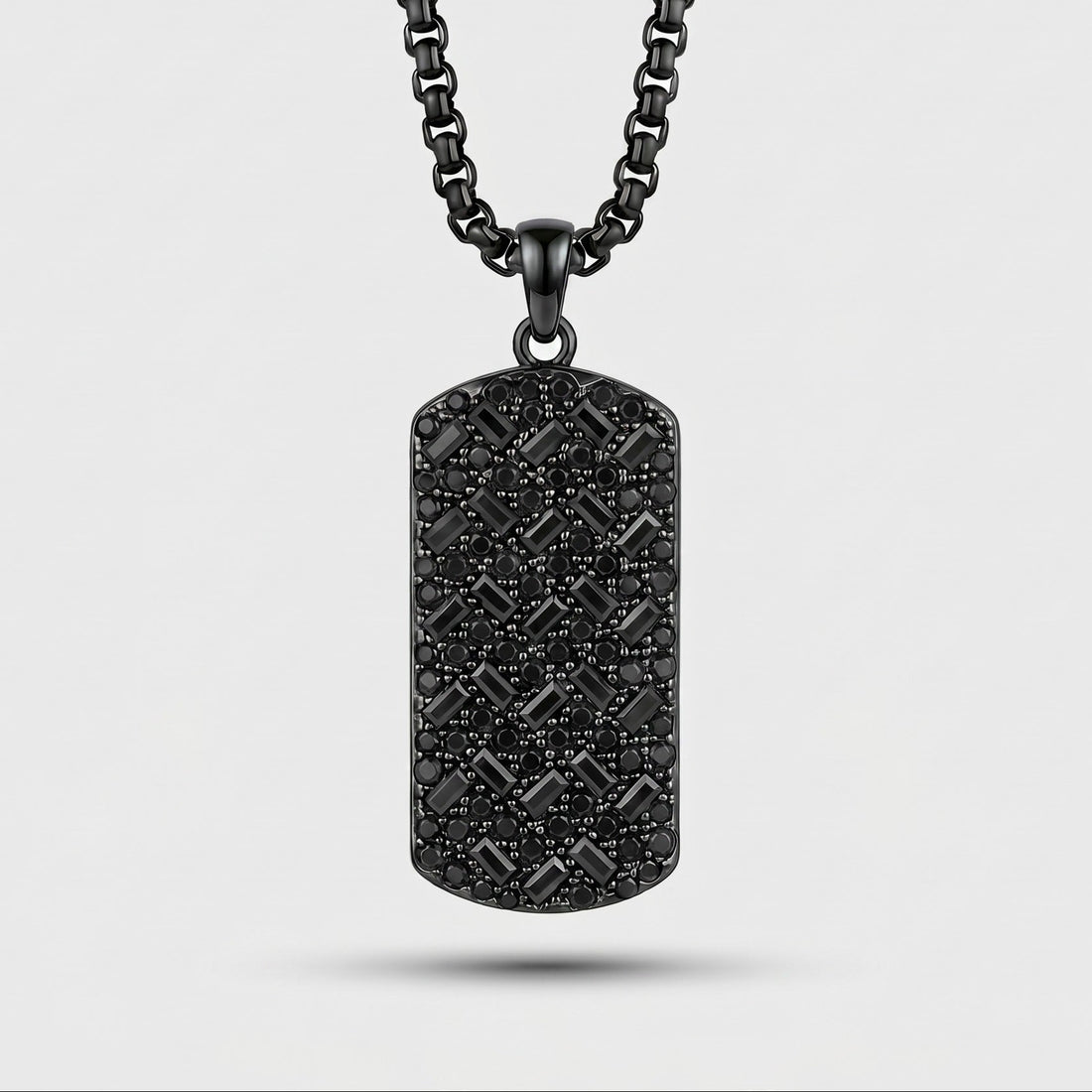 Black textured dog tag pendant on a chain against a light gray background