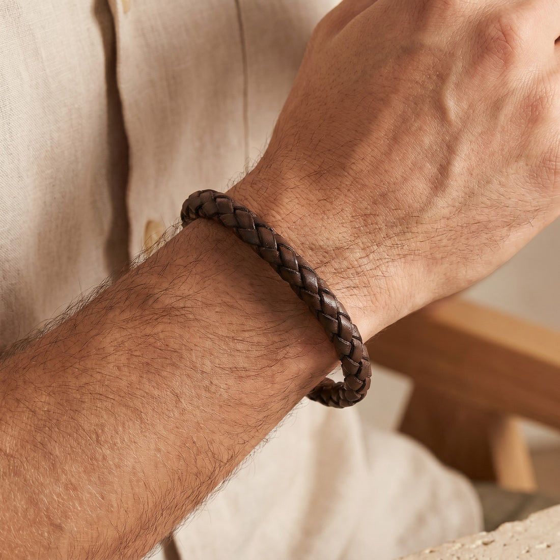 Close-up of a braided leather bracelet on a wrist with a neutral background