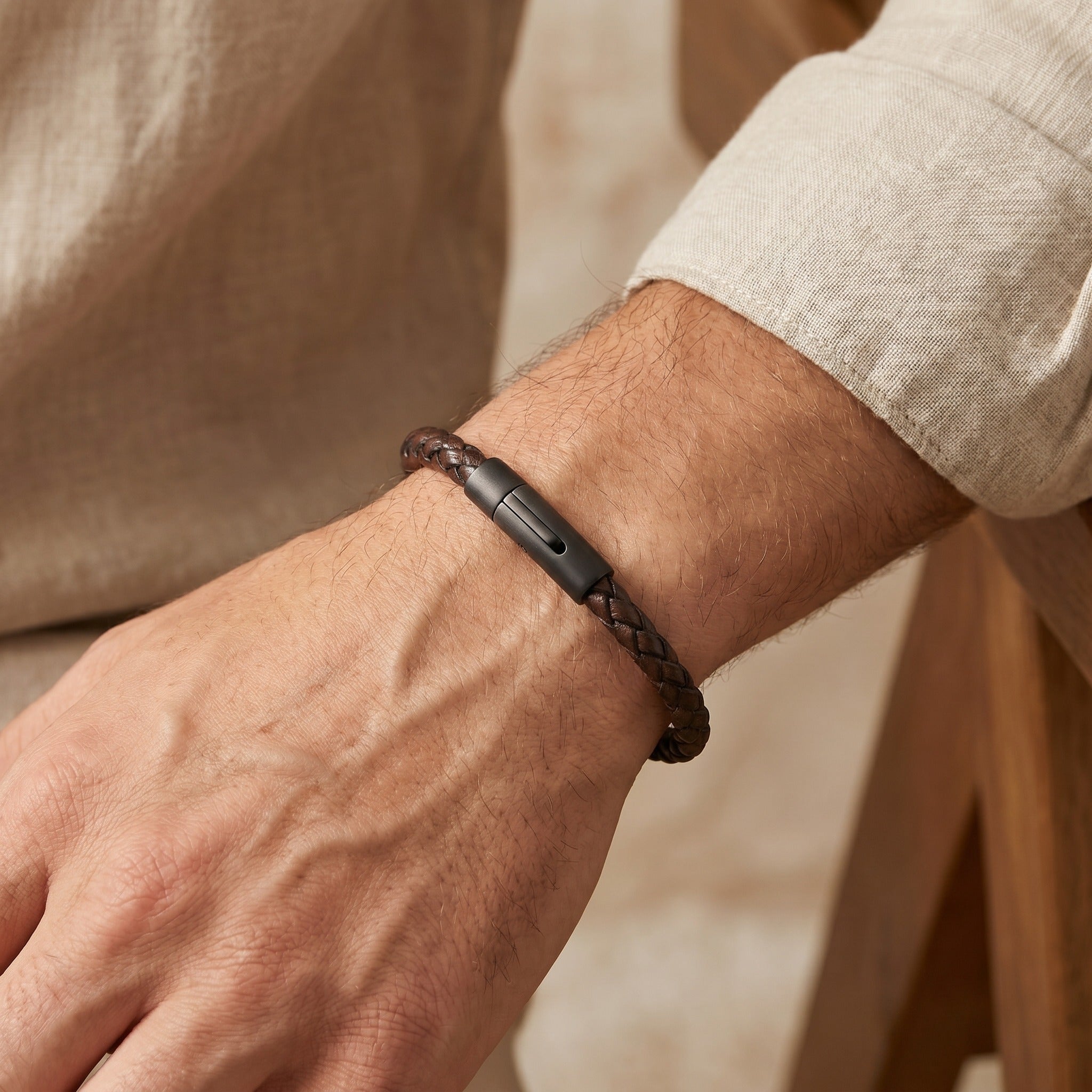 Close-up of a wrist wearing a black smartwatch with a braided brown leather strap.