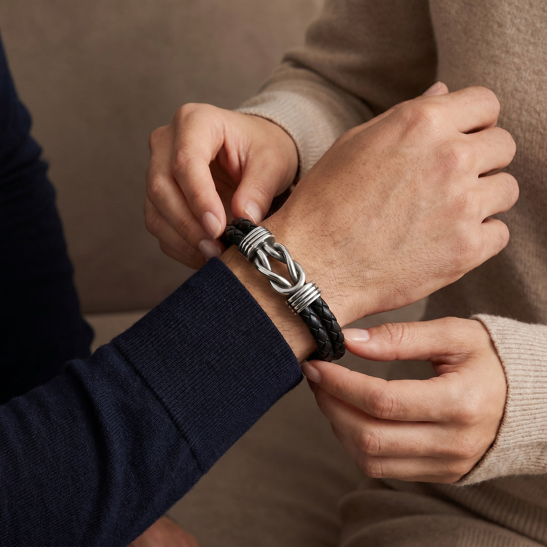 Person adjusting a braided leather and metal bracelet on another person's wrist.