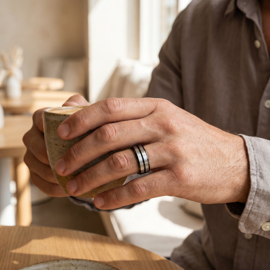 Hand holding a ceramic mug with a blurred indoor setting
