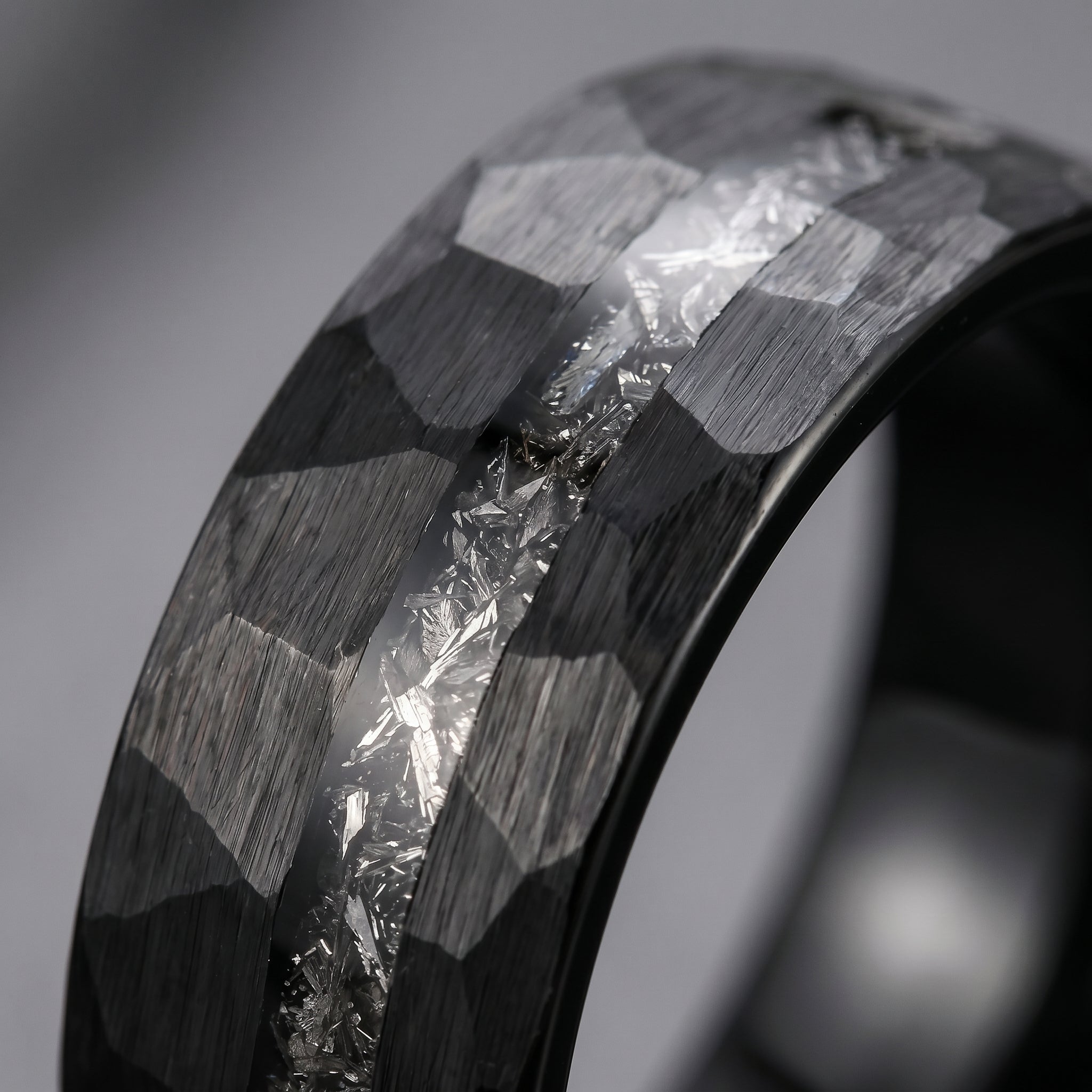 Close-up of a ring with geometric design and diamond-like material on a gray background