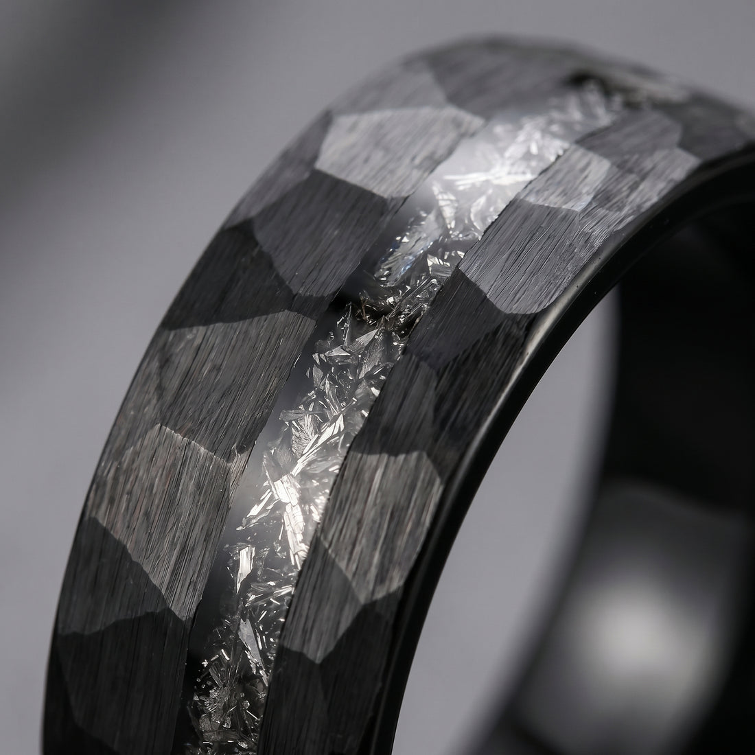 Close-up of a ring with geometric design and diamond-like material on a gray background