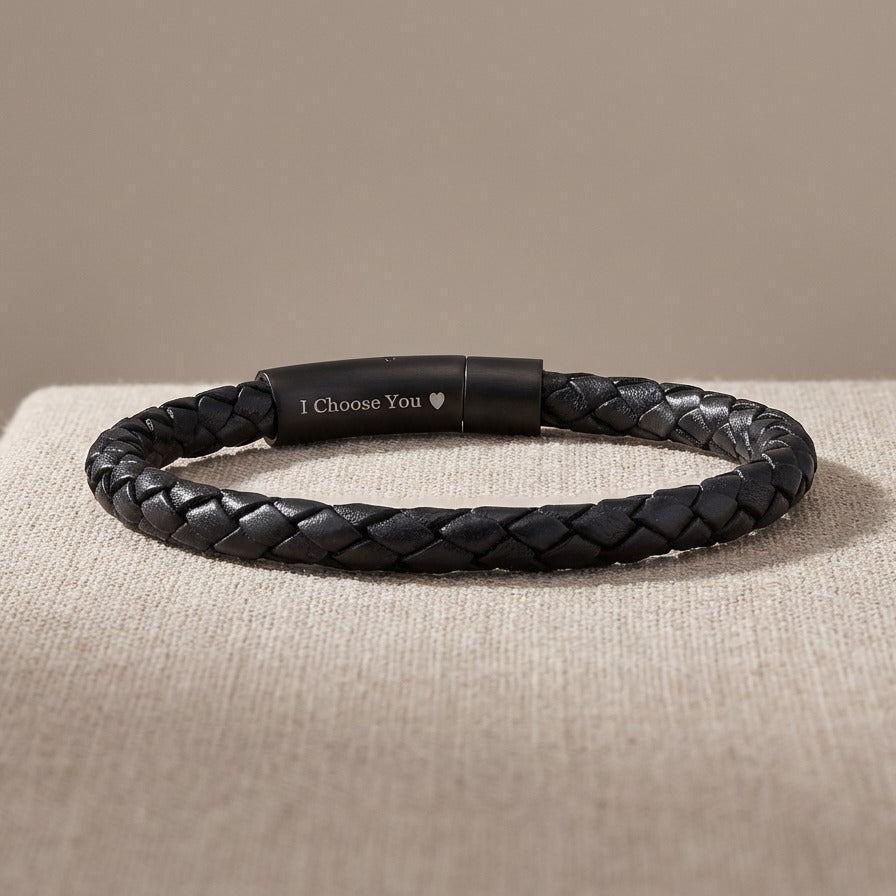 Black braided leather bracelet with a black clasp on a beige surface