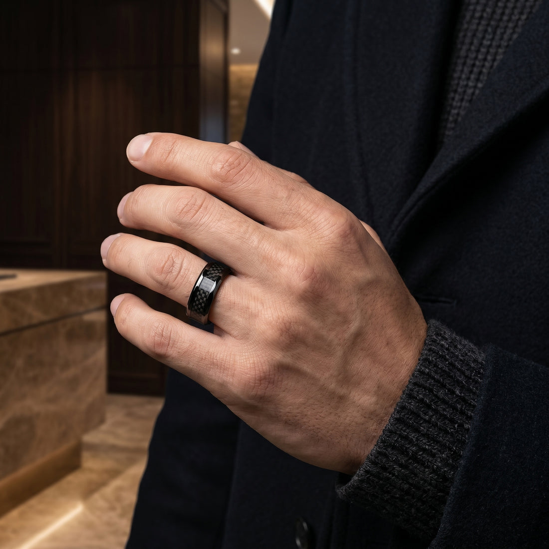 Hand wearing a black ring with a blurred background