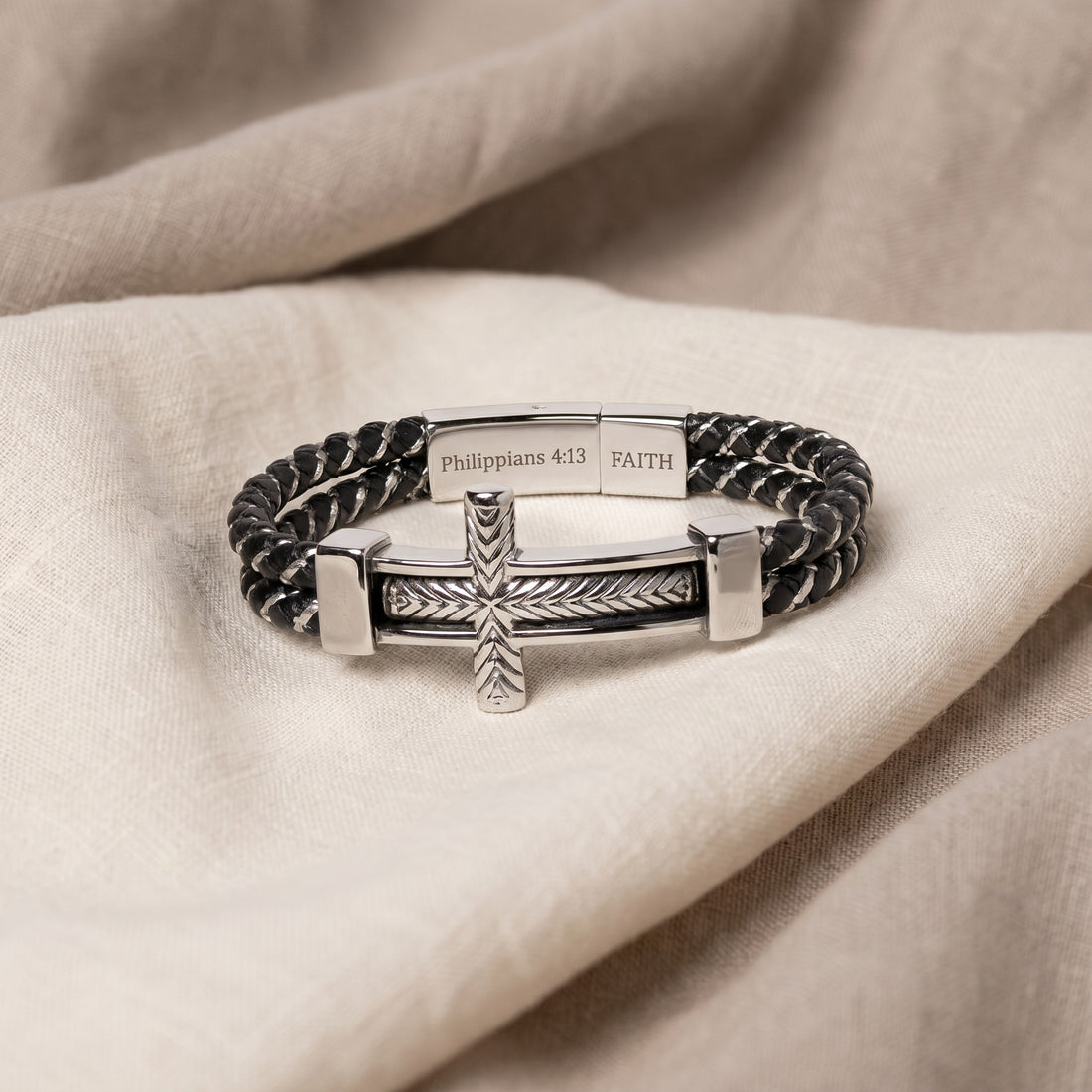 Bracelet with cross design and engraved text on a beige fabric background