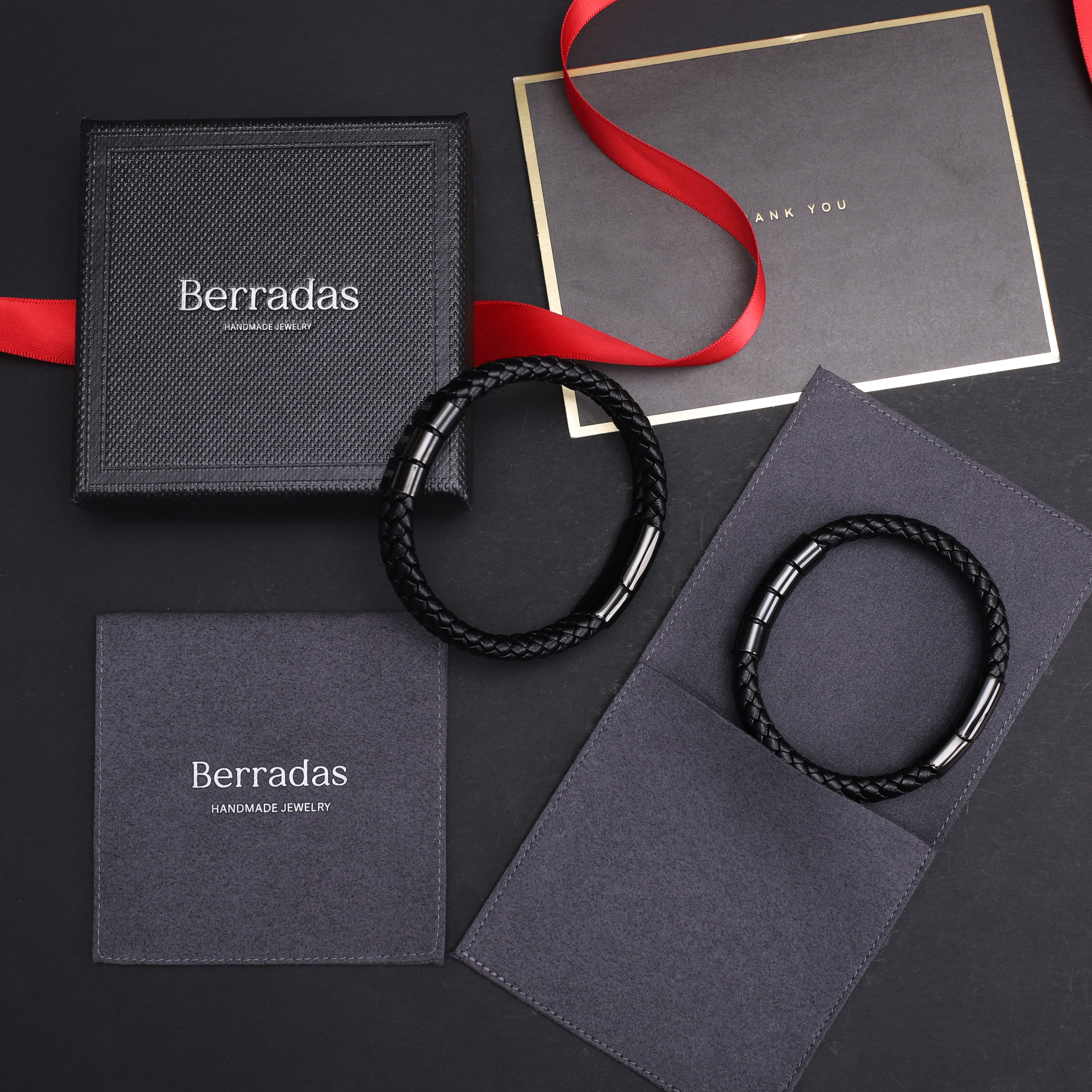 Berradas jewelry with black braided bracelets on branded packaging against a dark background