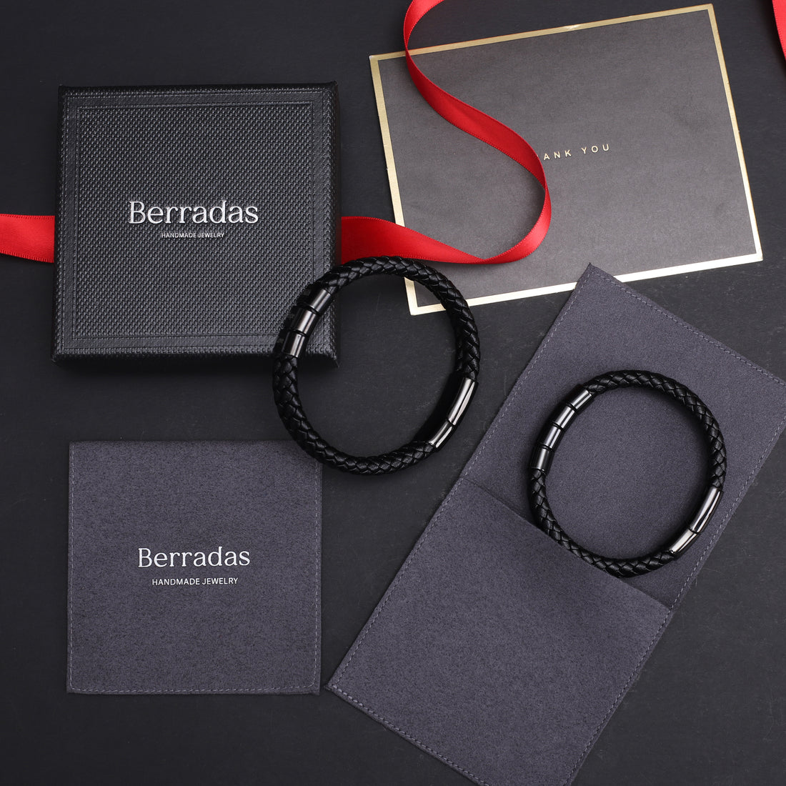 Berradas jewelry with black braided bracelets on branded packaging against a dark background