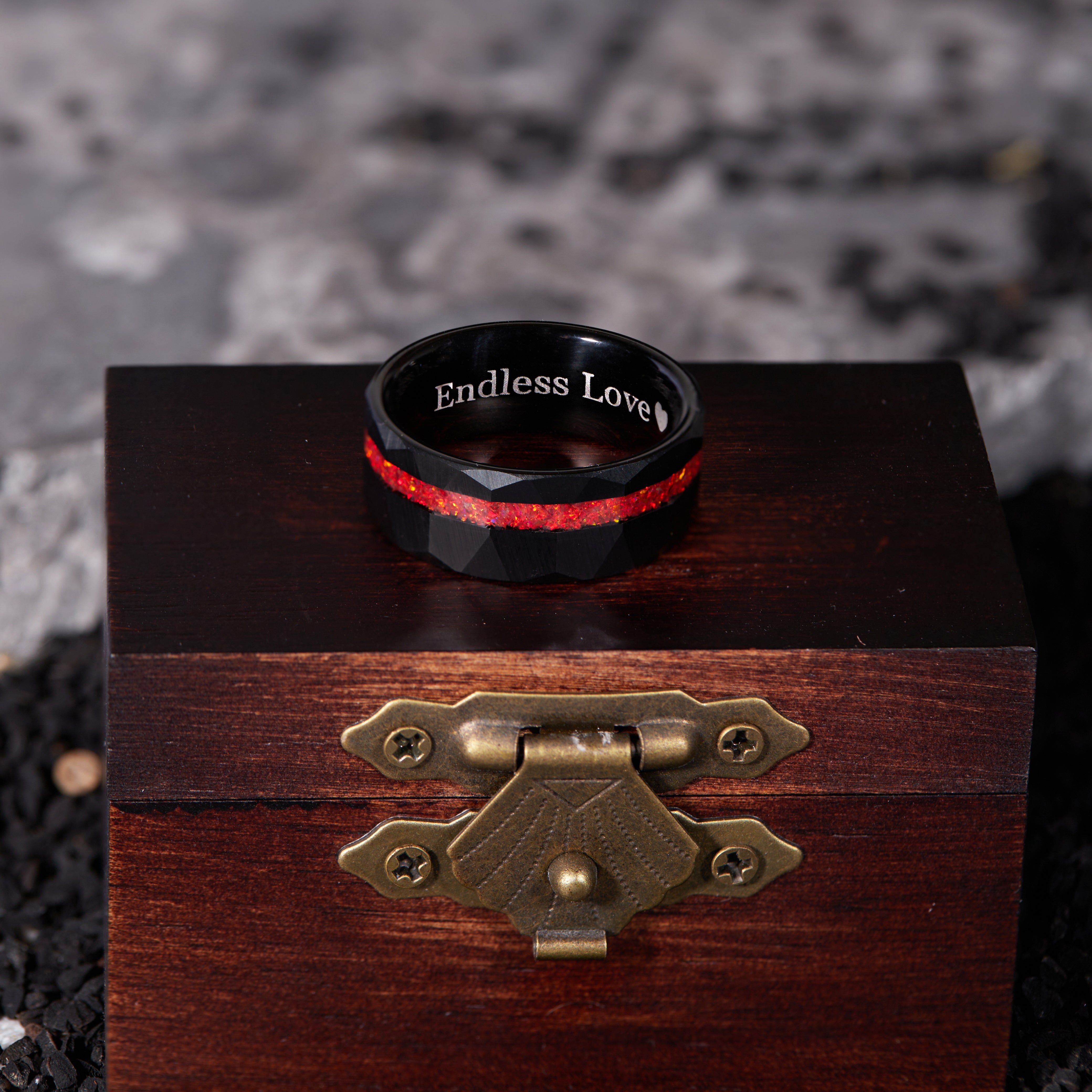 Elegant men's ring made of black tungsten, highlighted by a red opal centerpiece set in a rugged, hammered design.
