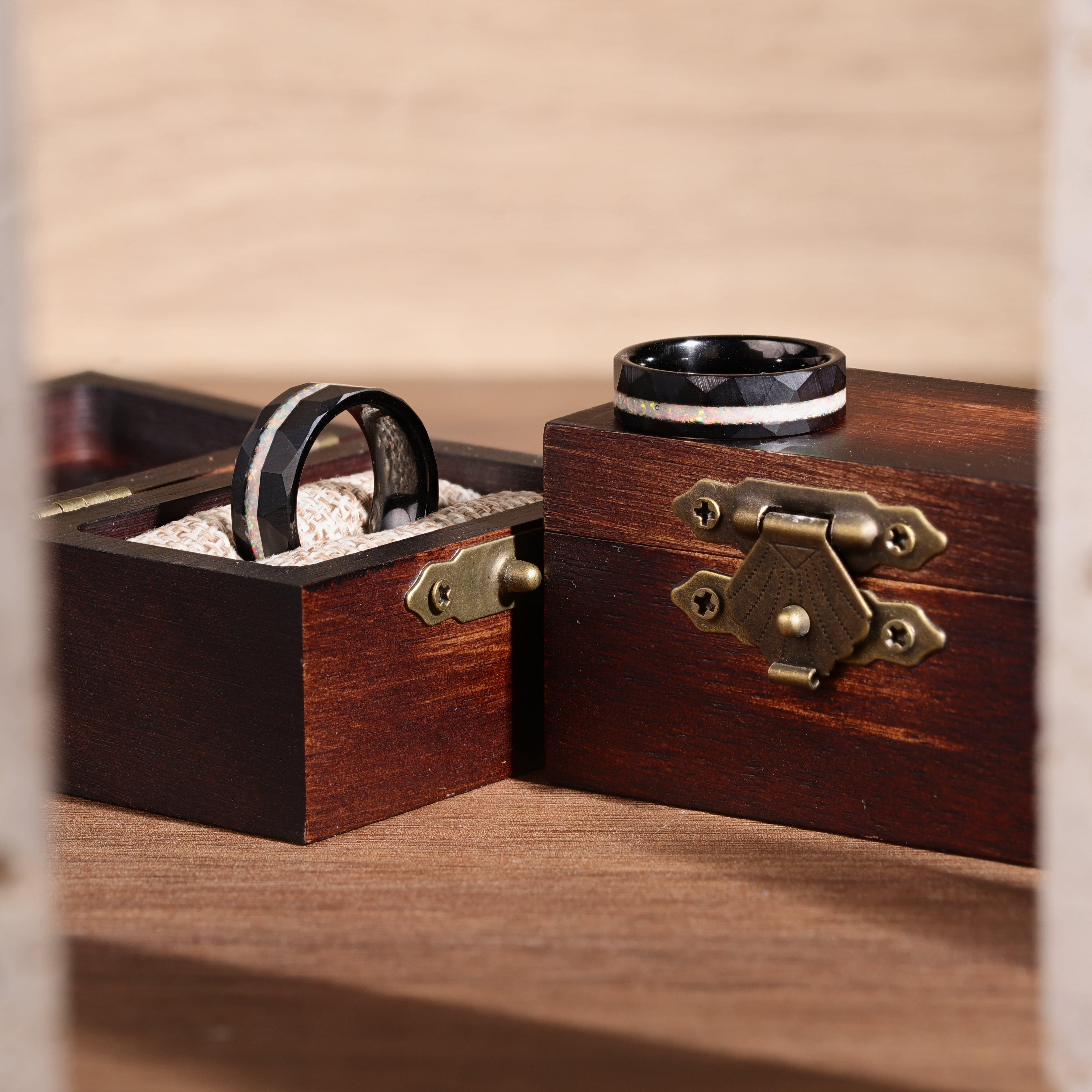 Two wooden jewelry boxes with rings inside on a wooden surface.